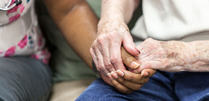 A caregiver holding a resident’s hand