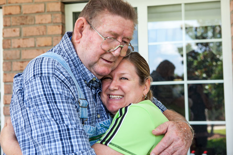 A resident and a family member hugging and smiling