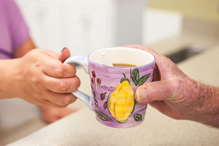A caregiver handing a resident a cup of coffee