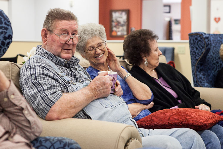 Three residents laughing together on a sofa